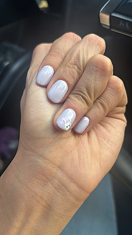 Uñas lila claro con un pequeño conejo blanco pintado en una