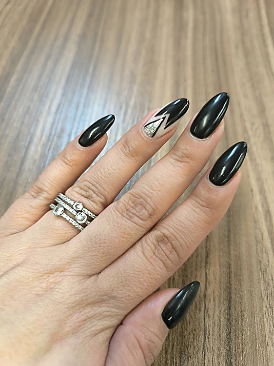 Uñas almendradas negras brillantes con un diseño geométrico en un dedo