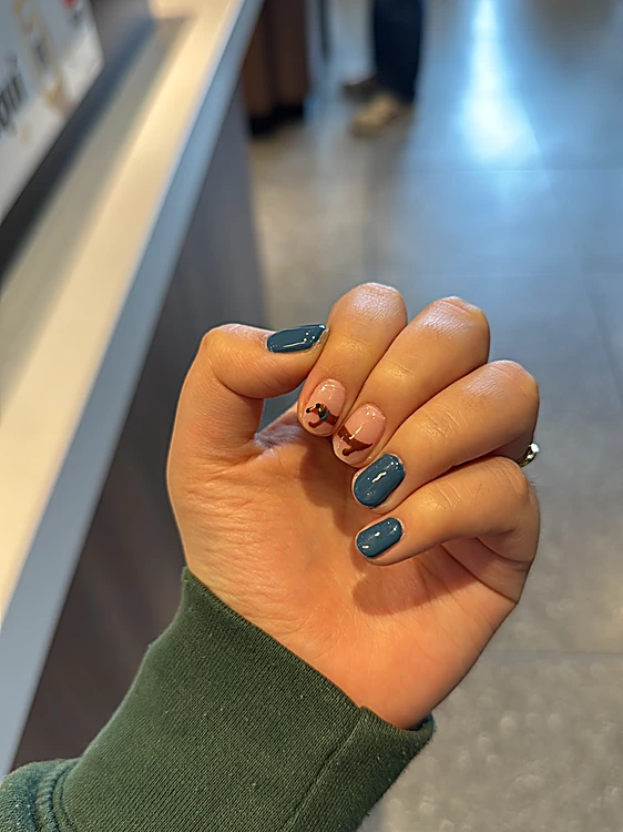 Uñas cortas azul petróleo con un diseño nude en dos dedos